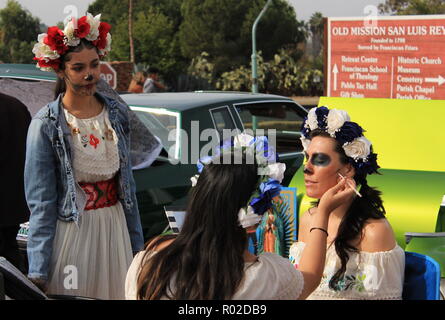 Trois jeunes woman putting on crâne en sucre (Catrina) maquillage pour célébrer le Jour des Morts Banque D'Images