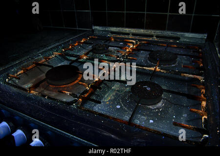 Qui, à première vue, une cuisinière à gaz révèle la saleté, huile, graisse, éclaboussé de cires grasses, les bactéries qui brillent sous la lumière UV montrant les pratiques d'hygiène Banque D'Images