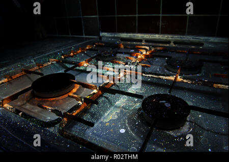 Qui, à première vue, une cuisinière à gaz révèle la saleté, huile, graisse, éclaboussé de cires grasses, les bactéries qui brillent sous la lumière UV montrant les pratiques d'hygiène Banque D'Images