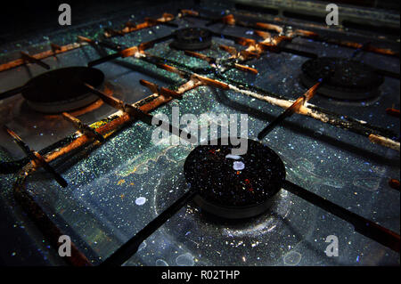 Qui, à première vue, une cuisinière à gaz révèle la saleté, huile, graisse, éclaboussé de cires grasses, les bactéries qui brillent sous la lumière UV montrant les pratiques d'hygiène Banque D'Images