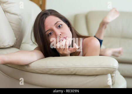 Jeune et jolie brunette woman reposant sur le canapé tout en pensant, dépressif, pensive, seul et sans défense à la maison Banque D'Images