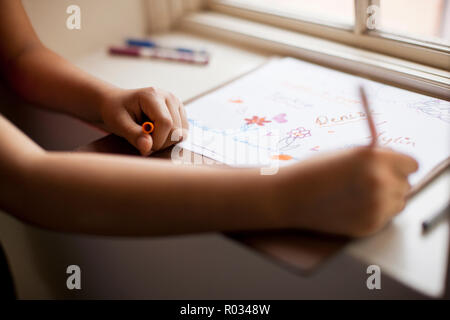 Les mains sur une fille de l'école dans un livre de coloriage. Banque D'Images