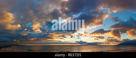 Vagues roulant sur une plage sous les nuages spectaculaires au coucher du soleil. Banque D'Images