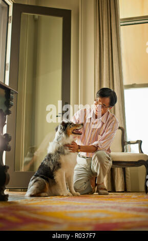 Smiling middle aged man petting son chien. Banque D'Images