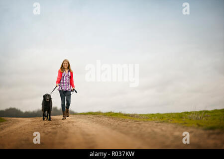 Portrait of a Teenage girl promener son chien le long d'un chemin de terre. Banque D'Images