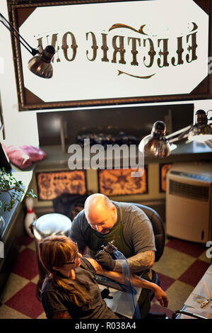 Woman getting son bras tatoué à un salon de tatouage. Banque D'Images