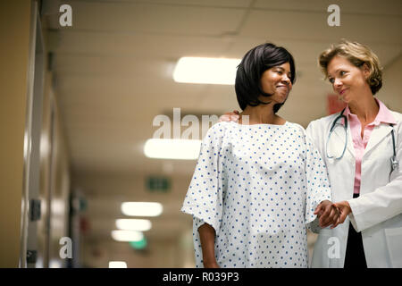 Médecin aider son patient à marcher dans le couloir pour la première fois après la chirurgie. Banque D'Images