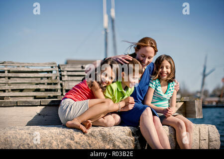 Mère assise avec ses enfants à quai. Banque D'Images