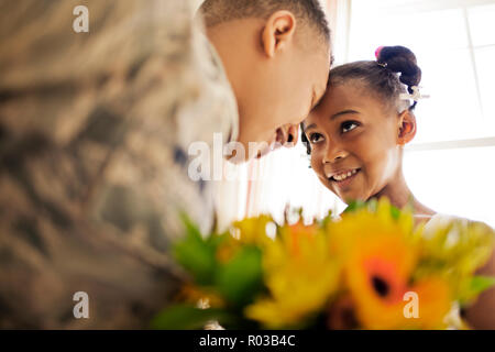 Soldat souriant de toucher leur front avec sa jeune fille dans leur maison. Banque D'Images