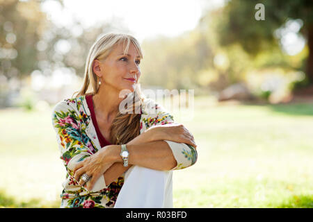 Mature Woman sitting in a park à pensif. Banque D'Images