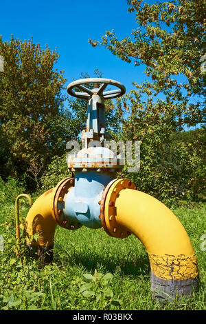 Grand tuyau de gaz en métal (avec un robinet sur une pelouse verte Banque D'Images