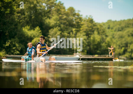Père et fils s'amusant paddleboarding sur la rivière. Banque D'Images
