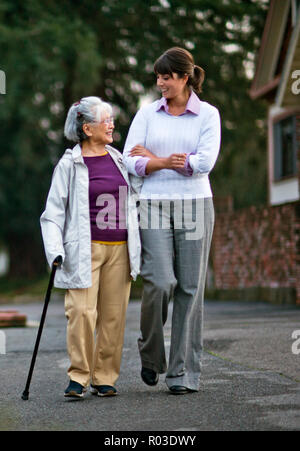 Vieille femme marchant bras dessus bras dessous avec son médecin. Banque D'Images