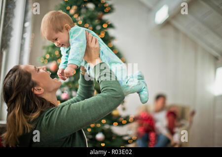 Mère joyeusement holding up sa petite fille. Banque D'Images