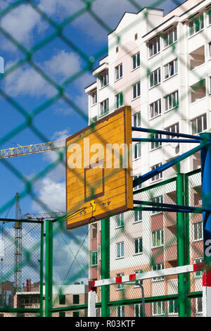 Un bouclier et un anneau en métal pour jouer au basket-ball dans la rue, d'un terrain de sport derrière une grille, près de la ville Banque D'Images