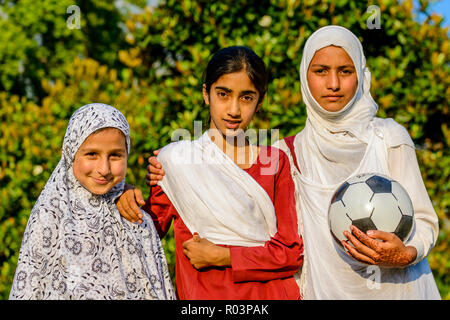 Un portrait de trois jeunes filles du Cachemire portant un football, deux d'entre eux couvrant leurs têtes par un blanc et un châle gris Banque D'Images