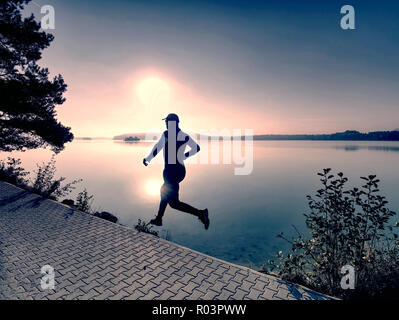 Trajet régulier au lac. L'homme en plein air sprint coureur nature pittoresque. Mettre en place la formation de l'athlète masculin trail running pour marathon. Banque D'Images