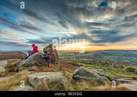 Beau paysage photographie d'enfants jouant sur les rochers coucher du soleil à Curbar Edge, parc national de Peak District, Derbyshire, Angleterre Octobre 2018 Banque D'Images