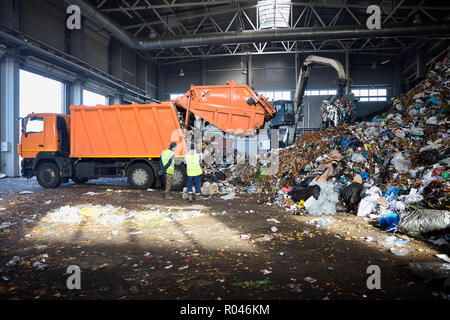 Deux travailleurs de l'usine de recyclage de processus de contrôle de déchargement de camion poubelle à ordures. Charges manipulateur ordures le convoyeur pour la poursuite du traitement d'un Banque D'Images