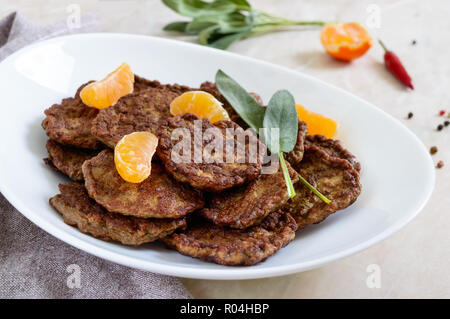 Escalopes de foie délicieux avec la mandarine sur une plaque blanche sur la table. Banque D'Images