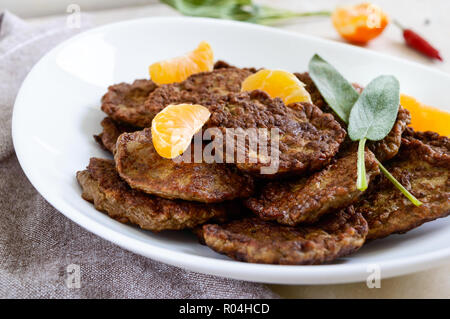 Escalopes de foie délicieux avec la mandarine sur une plaque blanche sur la table. Banque D'Images