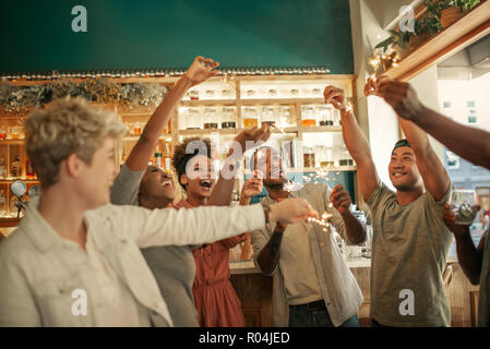 Divers jeunes amis célébrant dans un bar avec des cierges Banque D'Images