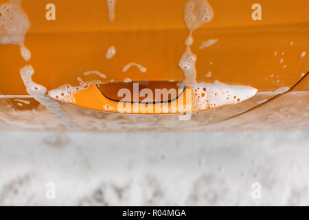 Poignée de porte de voiture jaune couverts avec du shampoing et de mousse au lavage en lave-auto. Banque D'Images