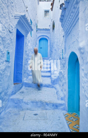 L'homme dans des vêtements traditionnels marocains marchant dans les rues de Chefchaouen, Maroc Banque D'Images