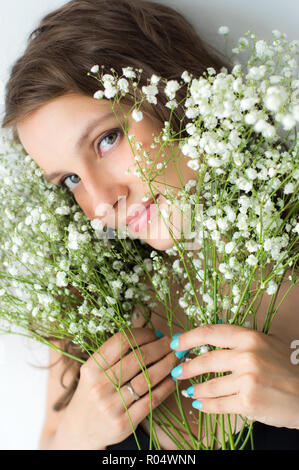 Femme avec bouquet de fleurs dans les mains , mur blanc sur fond Banque D'Images