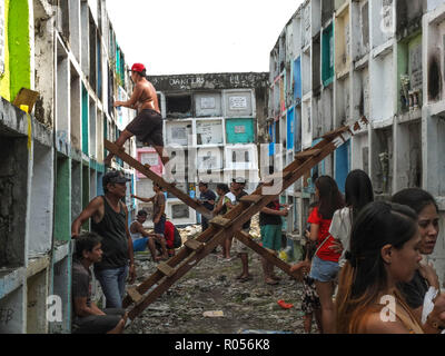 Manille, Philippines. 1er novembre 2018. Un homme de mettre une bougie avec une bouteille d'eau minérale à son plus proche parent décédé par l'utilisation d'une échelle en bois.Des millions de Philippins troupeau aux cimetières à travers le pays pour rendre visite à leurs défunts amoureux. Payer leurs respects à des êtres chers qui sont morts. C'est la tradition et la culture philippine. Credit : Josefiel Rivera SOPA/Images/ZUMA/Alamy Fil Live News Banque D'Images