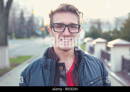 Portrait de jeune homme heureux dans les verres et les enduire debout sur street and smiling at camera Banque D'Images