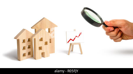 Loupe à la recherche à la maisons en bois stand avec flèche rouge vers le haut. Demande croissante de logements et l'immobilier. La croissance de la ville et de ses p Banque D'Images