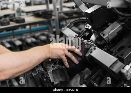 Utiliser l'homme pour faire une machine-outil des chaussures. Le convoyeur sur une usine de chaussures et de chaussures à semelle. La production de masse de chaussures. Banque D'Images