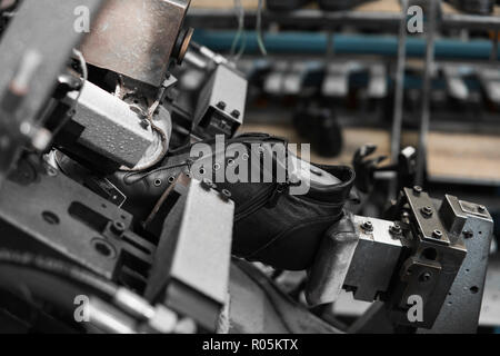 Utiliser l'homme pour faire une machine-outil des chaussures. Le convoyeur sur une usine de chaussures et de chaussures à semelle. La production de masse de chaussures. Banque D'Images