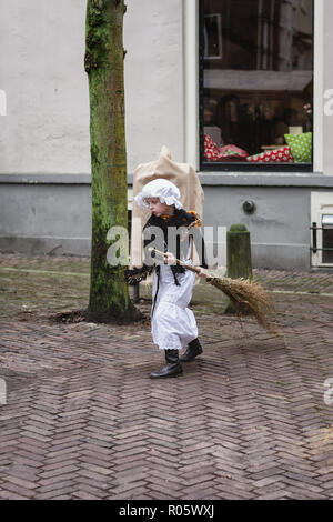 Deventer, Pays-Bas, le 21 décembre 2014 : Petite fille en robe costume victorien balaie la rue avec un balai pendant le festival Dickens dans de Banque D'Images