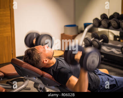 Jeune homme musclé, la formation pecs sur banc de sport Banque D'Images