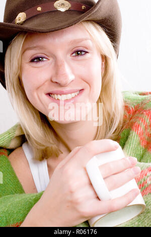 Belle fille dans un chapeau de cowboy avec tasse de thé enveloppé dans un plaid gros plan sur wite background Banque D'Images