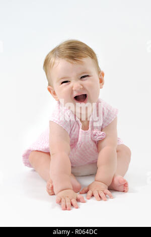 Un jeune et mignon femelle caucasien enfant rire joyeusement. Un portrait vertical image couleur en photo dans un studio. Banque D'Images