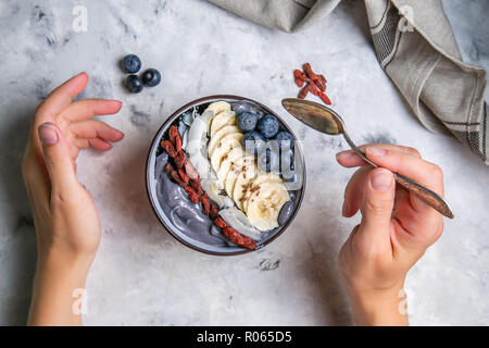 Femme mange du charbon activé detox bol de yogourt, vue du dessus Banque D'Images