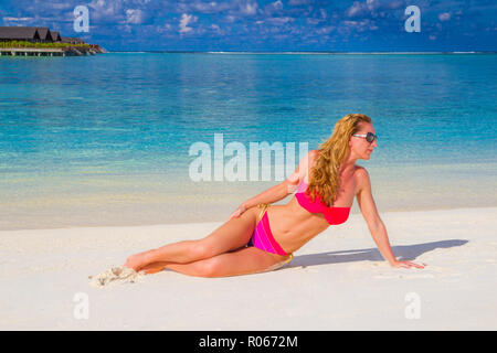Portrait of smiling young woman on beach et à la voiture en bikini rose et lunettes de soleil. Plage exotique avec copie espace, les femmes attirantes bénéficie d Banque D'Images