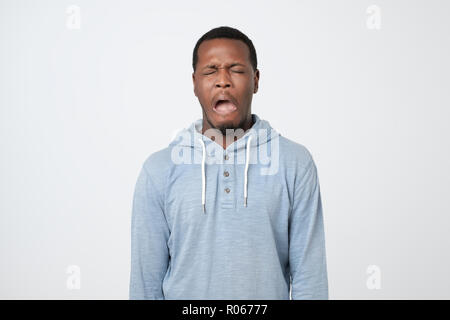 Young African man wearing blue shirt avec expression pleurer sur le visage. Banque D'Images