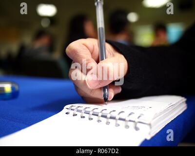 La photo en gros plan d'une part écrit sur un ordinateur portable à l'aide d'un stylo Banque D'Images