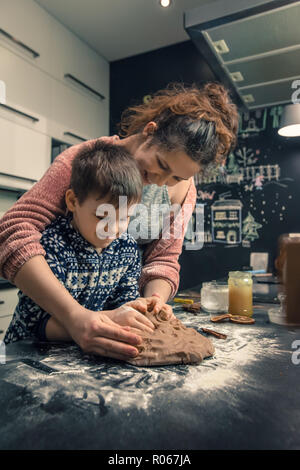 Heureux famille aimante dans la cuisine. La mère et l'enfant la préparation de la pâte, faire cuire des biscuits Banque D'Images