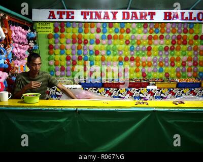 ANTIPOLO CITY, PHILIPPINES - le 27 octobre 2018 : un travailleur de préparer des ballons pour être utilisés comme cibles à son échoppe dans un carnaval. Banque D'Images