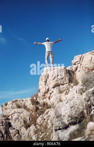 Young male rock climber sur le haut d'une falaise Banque D'Images