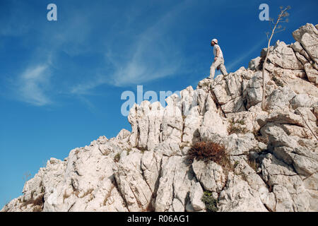 Young male rock climber sur le haut d'une falaise Banque D'Images