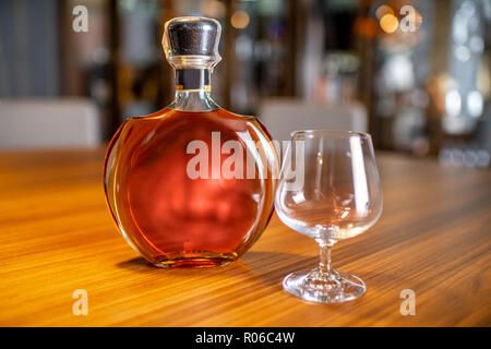 Bouteille de cognac avec le verre vide sur la table de salon à cigares Banque D'Images