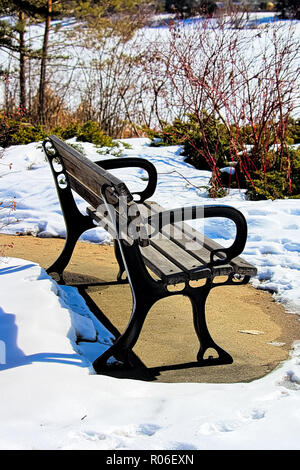 Un banc en bois en hiver avec pas de neige en dessous Banque D'Images