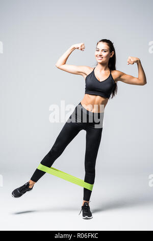 Femme l'exercice de faire d'entraînement pour les jambes avec des bandes élastiques sur fond blanc Banque D'Images