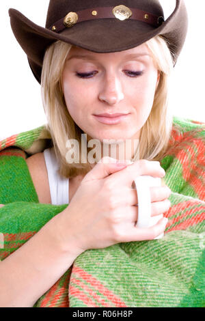 Belle fille dans un chapeau de cowboy avec tasse de thé enveloppé dans un plaid gros plan sur wite background Banque D'Images